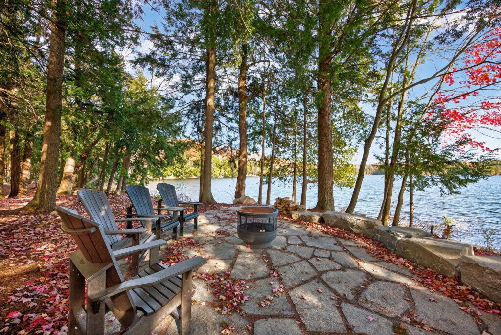 The lakeside patio of a log home transformed by Legacy North Construction Management. A cozy fireplace overlooking the lake. 