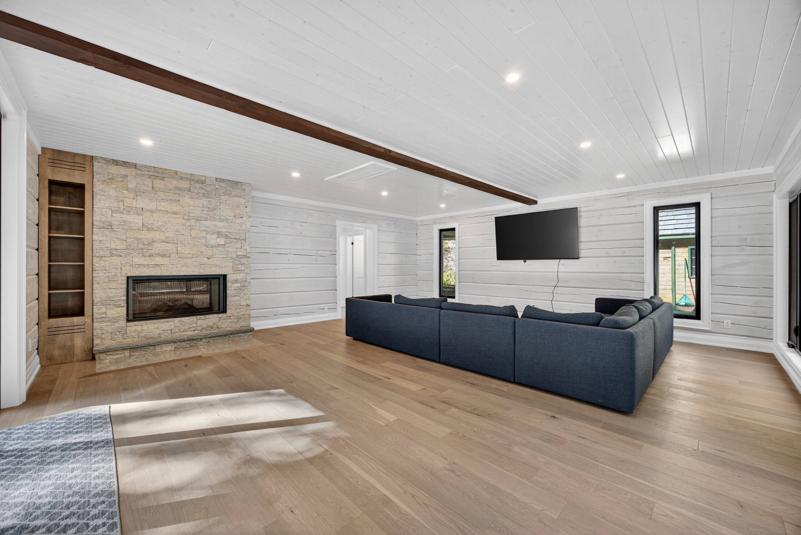 The sitting room, once a garage now offers a cozy space with expansive views of the lake and a two-way gas fireplace.