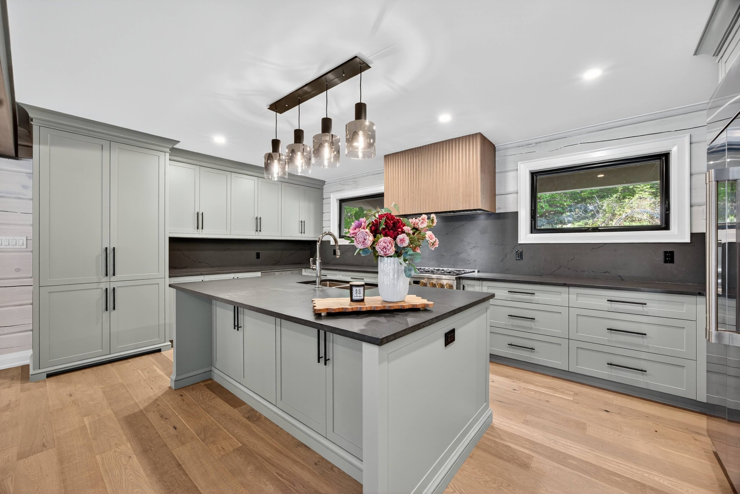 The kitchen of the re-finished home with modern light fixtures and a blend of neutral colours for a timeless appeal.